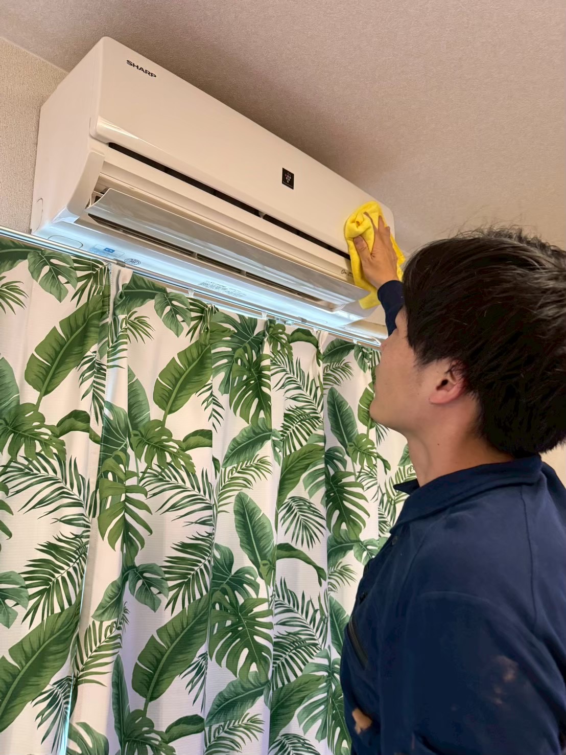 黄色いクロスでエアコン本体を拭き上げるN.Nスタイルのスタッフ